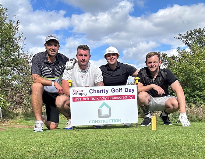 Four golfers gathered around hole sponsored by LJ Construction for Taylor Wimpey charity golf day