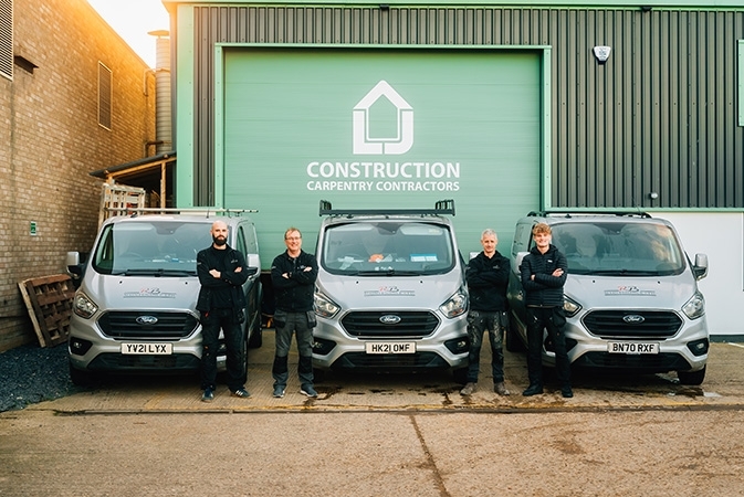 Customer care team next to vans outside LJ construction offices 