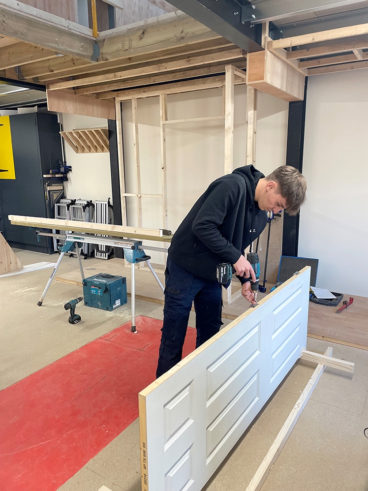 Trainee carpenter adding hinges to a door ready for hanging