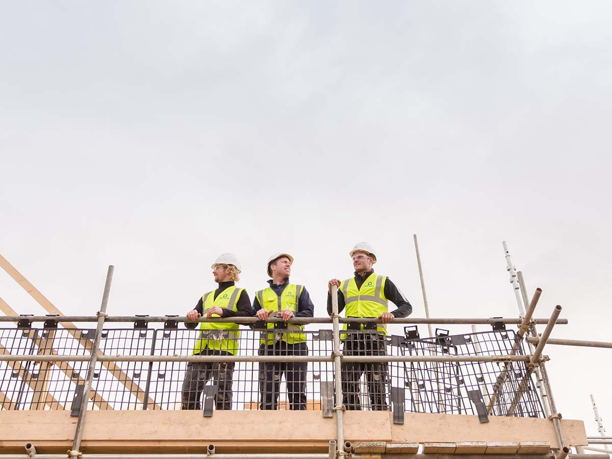 Carpentry contractors surveying site atop scaffolding